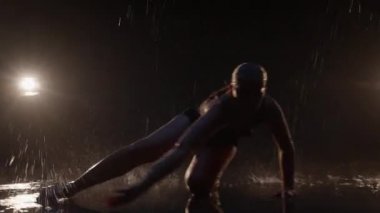 Sensual Young Woman Dancer Performing in the Rain in Dark Studio Against Black Backdrop and with Spotlights On. Water Drops Falling on the Floor Imitating Rain Shower. Dolly In and Out Shot