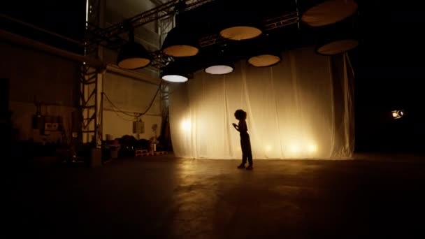 ソフトウォームバックライト付きステージカーテンに対してスタジオで行うプロのダンサー アフロヘアスタイルのアフリカ系アメリカ人女性が点滅スポットライトで踊る スローモーション ズームインショット — ストック動画