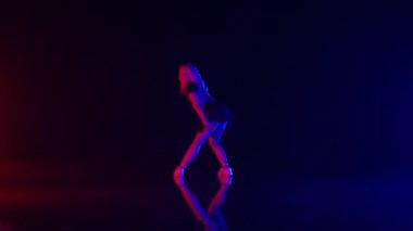 Uzun Sarı Saçlı Seksi Genç Kadın Renkli Sahne Işıkları Stüdyosunda Dans Ediyor. Karanlık Arkaplan 'a Karşı Güzel Performans ve Yerde Yansımalar. Yavaş Hareket Görüntüsü