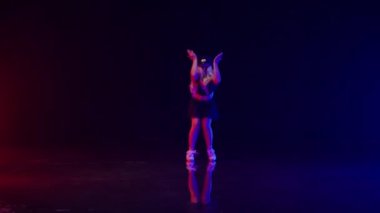 Polis Şapkalı Seksi Genç Kadın Renkli Sahne Işıkları Stüdyosunda Dans Ediyor. Şapkayı fırlatıp atıyor. Karanlık Arkaplan 'a Karşı Güzel Performans ve Yerde Yansımalar. Yavaş Hareket Görüntüsü