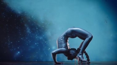 Esnek Kadın Akrobat Parlak Kıyafet Giyiyor ve Yüksek Topuklular Yıldız Alanına Karşı Sahnede Sahne alıyor. İnanılmaz Bir Performansın Gizemli Atmosferi. Sabit Çekim