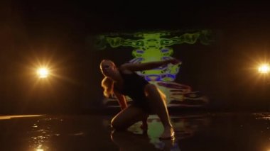 Stüdyoda Dans Eden Sanatçı Genç Kadın. Karanlık Animasyon Arkaplan ve Sahne Işıklarına Karşı Dansçı. Kamera Dansçıyı Takip Ediyor