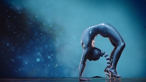 星の宇宙を背景に舞台上で活躍する柔軟性の高い女性コンストラクター 驚異的なパフォーマンスの神秘的な雰囲気 静的ショット — ストック動画