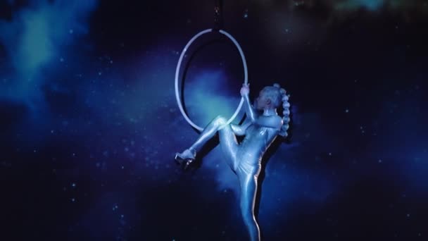 星空を背景にした空中輪で輝く衣装とハイヒールを身につけた柔軟な女性コンストラクター 驚異的なパフォーマンスの神秘的な雰囲気 静的ショット — ストック動画