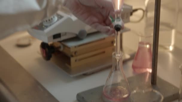 研究室内の医療用フラスコに液体の流れを調整する科学者の手によるショットを閉じる — ストック動画
