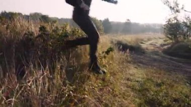 Bald Head Turist Sırt Çantası Yürüyüşleri Ormanda Uzun Çimenler Çayırında. Hillock 'tan Açıklık ve İleriye Yürüme' ye atlar. Kamera Adamı Takip Ediyor