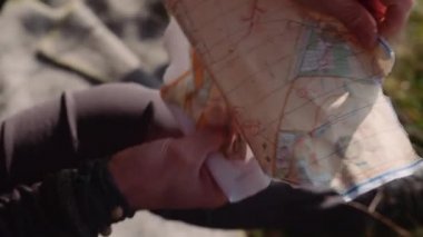 Mans Hands 'in yakın çekimi bir parça kağıt haritasını açar ve güzergahı kontrol eder. El bilgisayarı görüntüsü