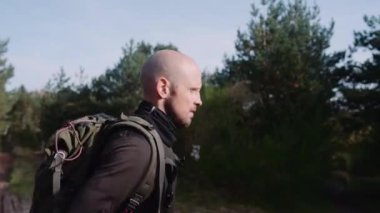 Ormanda Sırt çantalı Kel Turist Yürüyüşü. Ha 'nın elinde kağıt harita var. Kamera adamı takip ediyor. Orta Çekim