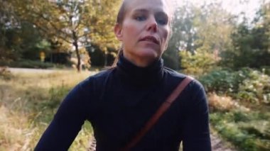 Sabah güneşinin yumuşak ışığında asfalt yolda bisiklete binen bir kadın turistin portresi. El bilgisayarı görüntüsü