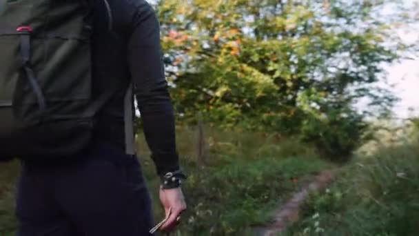 バックパック付きの大胆な頭の男の観光客のサイドビュー森の中の小さな歩道に沿ってハイキング カメラは男の後を追う — ストック動画
