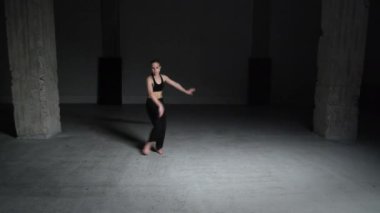 Sarı Saçlı Enerjik Genç Kadın Koreografı Siyah Üstlü ve Pantolon Giyen Beton Duvarlarla Dans Eden Stüdyoda. Geniş Sabit Çekim