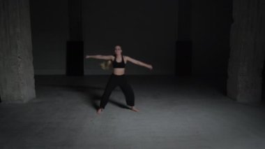 Sarı Saçlı Enerjik Genç Kadın Koreografı Siyah Üstlü ve Pantolon Giyen Beton Duvarlarla Dans Eden Stüdyoda. Geniş Sabit Çekim