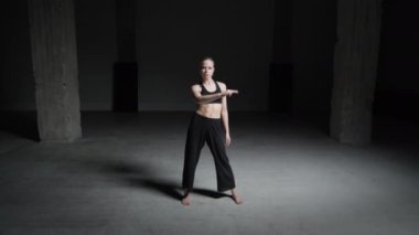 Sarı Saçlı Enerjik Genç Kadın Koreografı Siyah Üstlü ve Pantolon Giyen Beton Duvarlarla Dans Eden Stüdyoda. Geniş Sabit Çekim