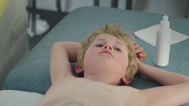 病院のベッドの上に寝そべっている少年の肖像 男の子はカメラを見ている スローモーション Dolly Shot — ストック動画