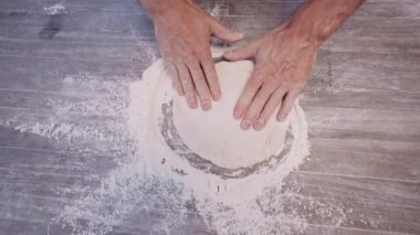 Yavaş çekim, adamın hamur şeklini pizza tabanına çevirdiği, elinde un, elinde de açık masa resmi.