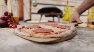 Yavaş çekim, Pepperoni Pizza 'yı açık hava pizzasına koyarken çekiliyor.