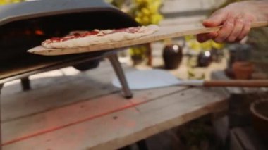 Yavaş çekim, Pepperoni Pizza 'yı açık hava pizzasına koyarken çekiliyor.