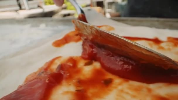 追踪慢动作近身男子用勺子将番茄比萨酱汁倒在室外生比萨槽上的镜头 — 图库视频影像