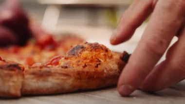 Yavaş çekim el kamerasında, adamın taze pişmiş pizzadan bir dilim aldığı fotoğraf.
