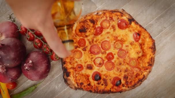 人往樱桃番茄和红洋葱旁边的新鲜烘烤比萨上浇辣椒油的头顶慢镜头慢镜头 — 图库视频影像