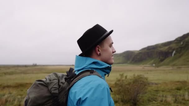 一名男子游客走向冰岛著名的塞尔贾兰多斯瀑布的肖像侧视图 相机跟随人 — 图库视频影像