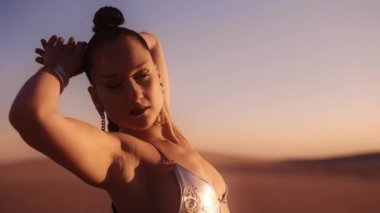 Bikini üstte güzel bir genç kadının çölde hareketli ve poz verirken orta yavaş çekim çekimi