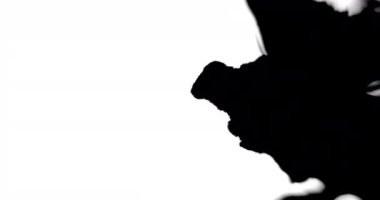 Siyah mürekkep beyaz yüzeye yayılırken yakın plan çekimleri.