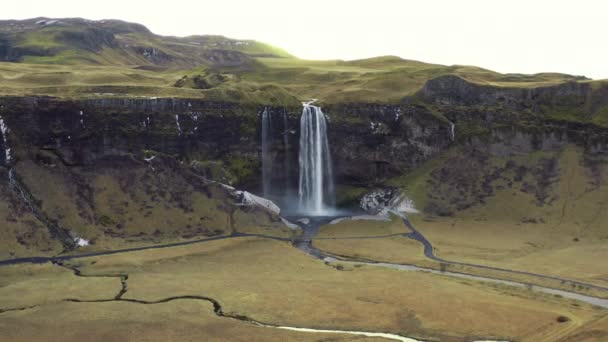 アイスランドの風景の中でSeljalandsfoss滝のワイドパンニングドローンショット — ストック動画
