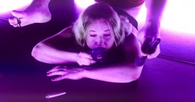 El kamerasında, göz kapaklarına makyaj yapmak için ayaklarında fırça tutarak yerde yatan kadın akrobatın orta boy fotoğrafı.