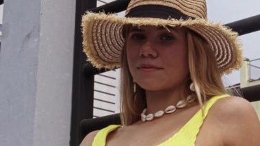 Güneş Şapkalı Güzel Kadın ve Sarı Mayo 'nun havuz başında gülümseyerek kameraya baktığı orta boy ağır çekim.