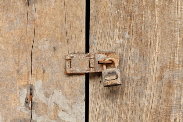 Porta de madeira velha trancada com cadeado enferrujado — Fotografia de Stock