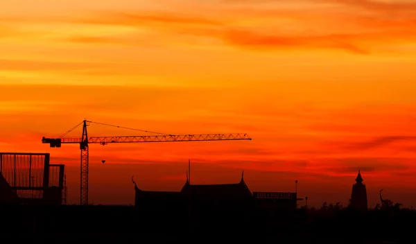 Grues de construction industrielle et bâtiment au lever du soleil — Photo