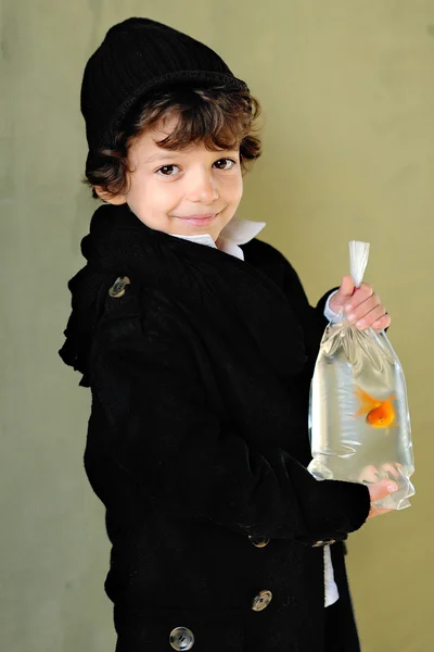 Porträt eines kleinen stylischen Jungen im Freien mit einem Goldfisch — Stockfoto