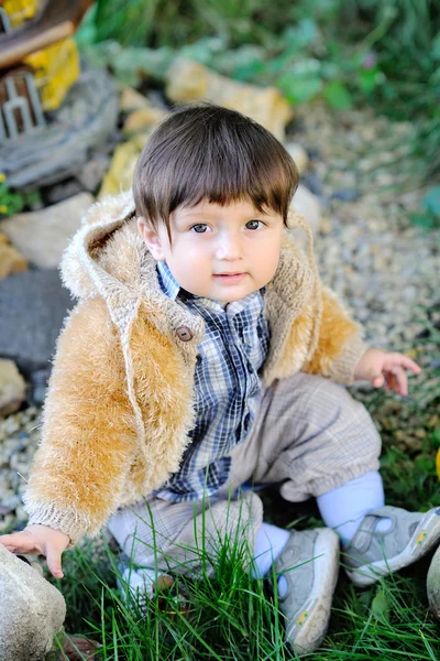 Lindo bebé sentado en la hierba al aire libre en chaqueta de otoño —  Fotos de Stock