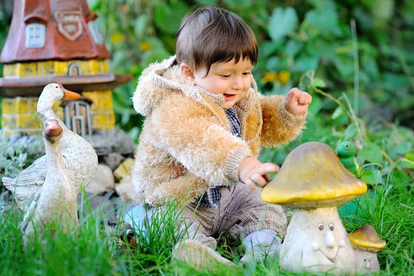 Roztomilé dítě sedící v trávě venku v podzimní bunda — Stock fotografie