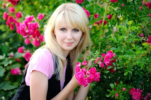 Retrato de una hermosa chica en un jardín de rosas —  Fotos de Stock