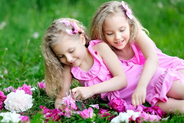 Portrait of two twins with peonies — Stock Photo, Image