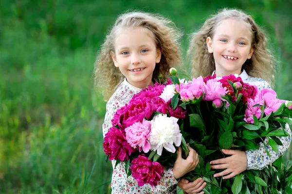 Portrait of two twins with peonies — Stock Photo, Image