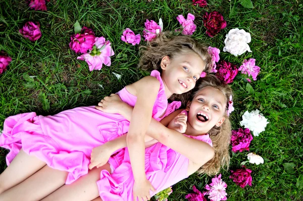 Portrait of two twins with peonies — Stock Photo, Image