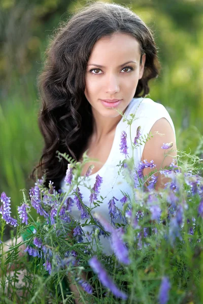 Hermosa chica en un campo con flores en flor —  Fotos de Stock
