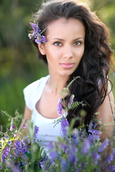 Bella ragazza in un campo con fiori in fiore — Foto Stock