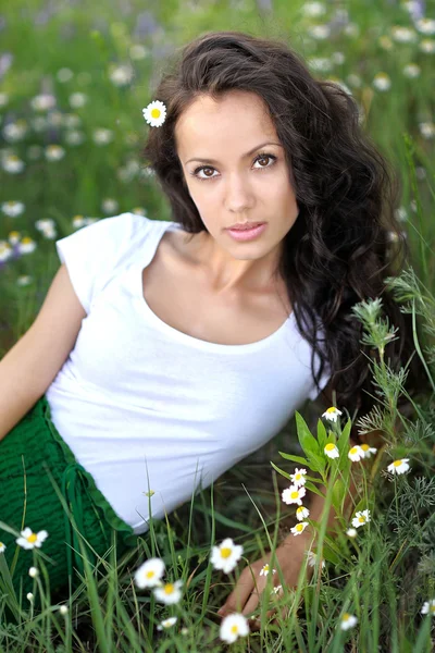 Hermosa chica en un campo con flores en flor — Foto de Stock