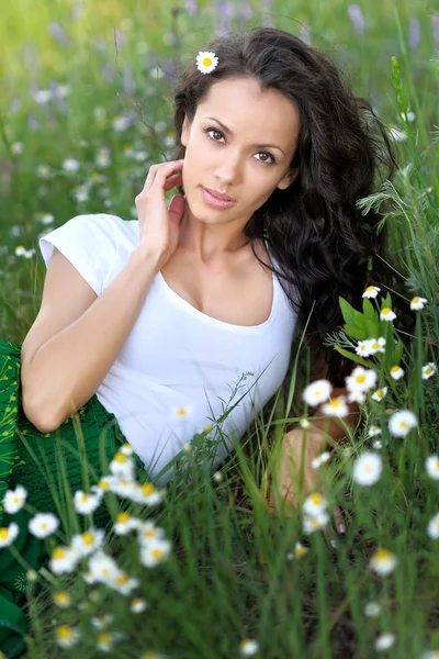 Menina bonita em um campo com flores florescendo — Fotografia de Stock