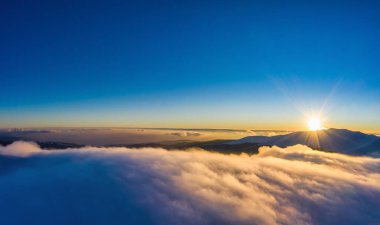 Soğuk bir kış akşamında sisli ve günbatımlı güneşli dağların ve kayaların büyüleyici manzarası. Sert kış doğa kavramı