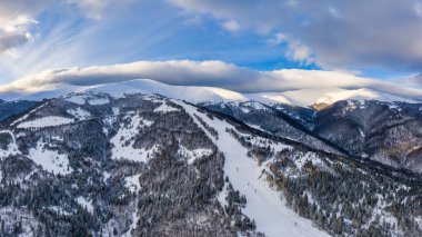 Bulutlu bir günde, bir kış dağ ormanının mistik manzarasının havadan görünüşü. Kuzey ülkelerinin acımasız güzelliği kavramı. Kopyalama alanı