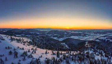 Güneşli bir günde, kar ve köknar ağaçlarıyla kaplı dağ tepelerinin manzarası güneşli ve mavi gökyüzü. El değmemiş Doğa Güzelliği Konsepti