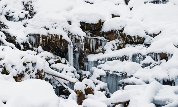 Pequeña cascada de agua fría fluye entre las piedras cubiertas de nieve —  Fotos de Stock