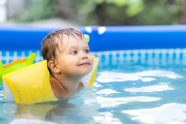 Üst kollu çocuk bahçedeki havuzda yüzüyor. — Stok fotoğraf