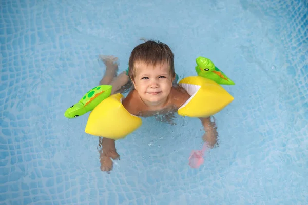 Üst kollu çocuk bahçedeki havuzda yüzüyor. — Stok fotoğraf