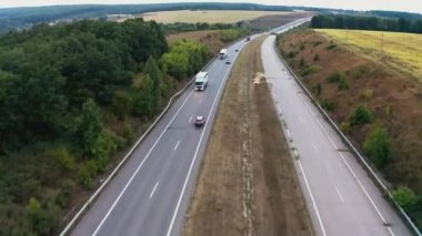 Arabalar ağaçlar arasında uzanan uzun bir patikadan geçiyor.